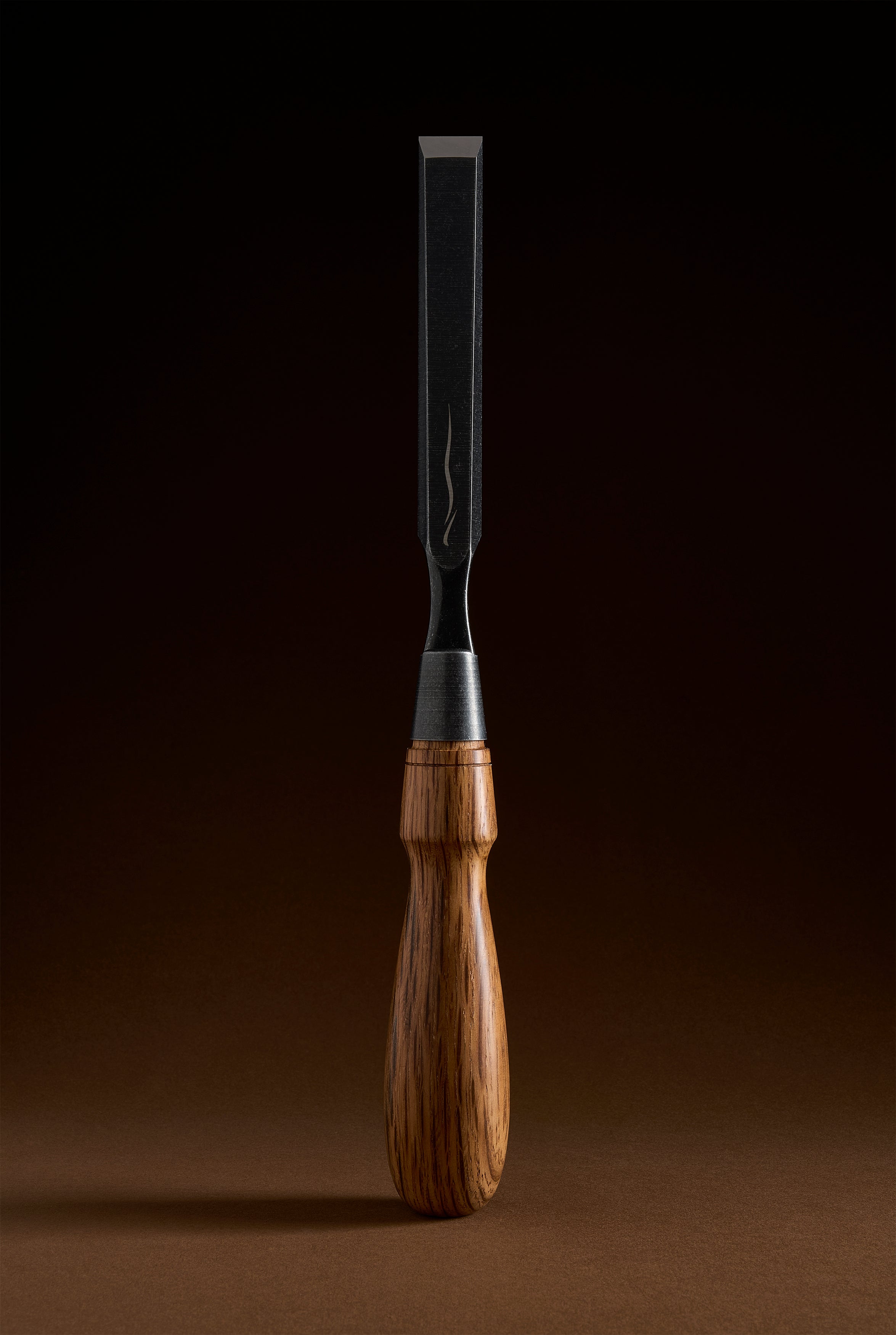 Medium-width Y-2 chisel on end, dark blade tapering to a polished edge, ferrule and shaped wooden grip below