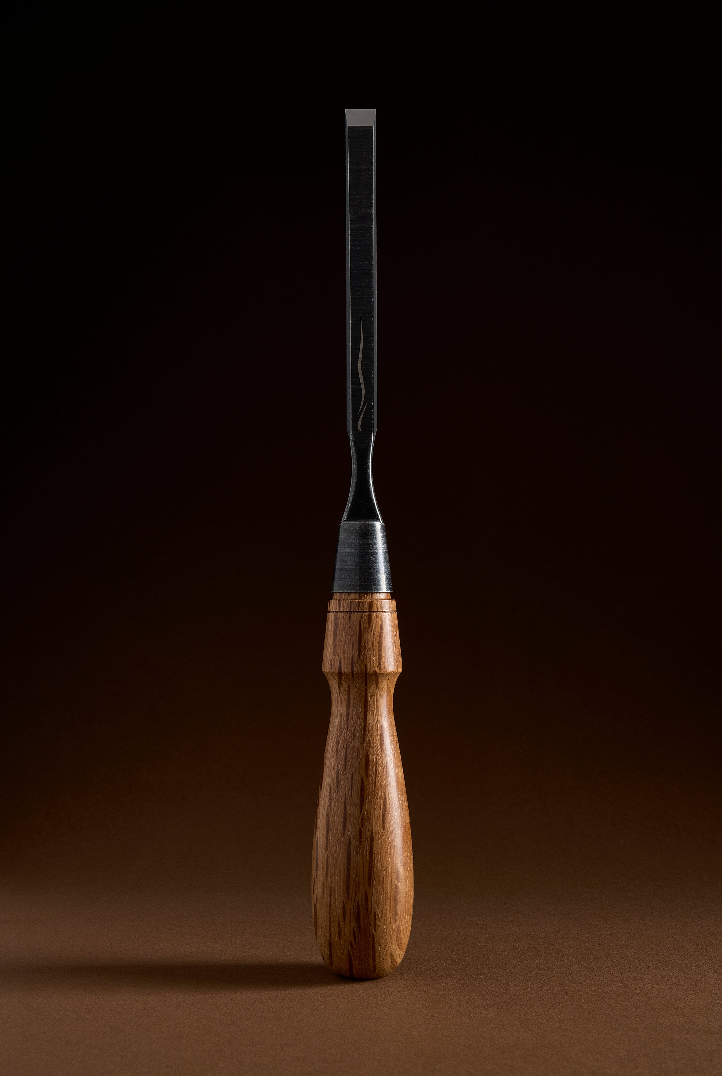 Narrow Y-2 chisel standing upright, slim dark blade meeting the steel ferrule and turned handle