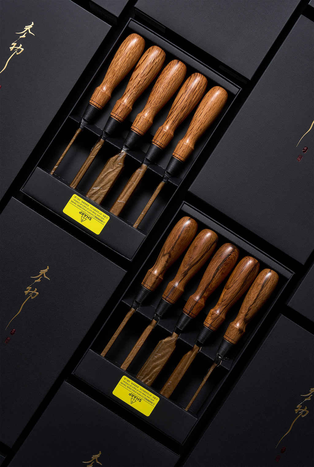 Two boxed Y-2 chisel sets angled across black gift boxes with gold brush calligraphy, blades wrapped in paper