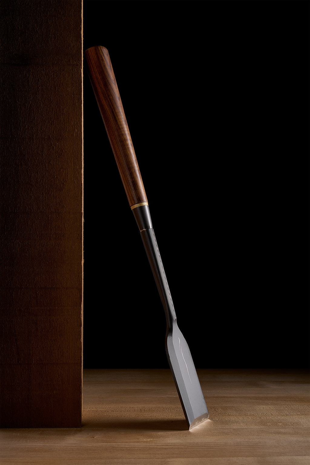 Zen-Wu DC-1 paring chisel standing against a timber, the edge resting on the bench top, full length from jatoba handle to blade in view