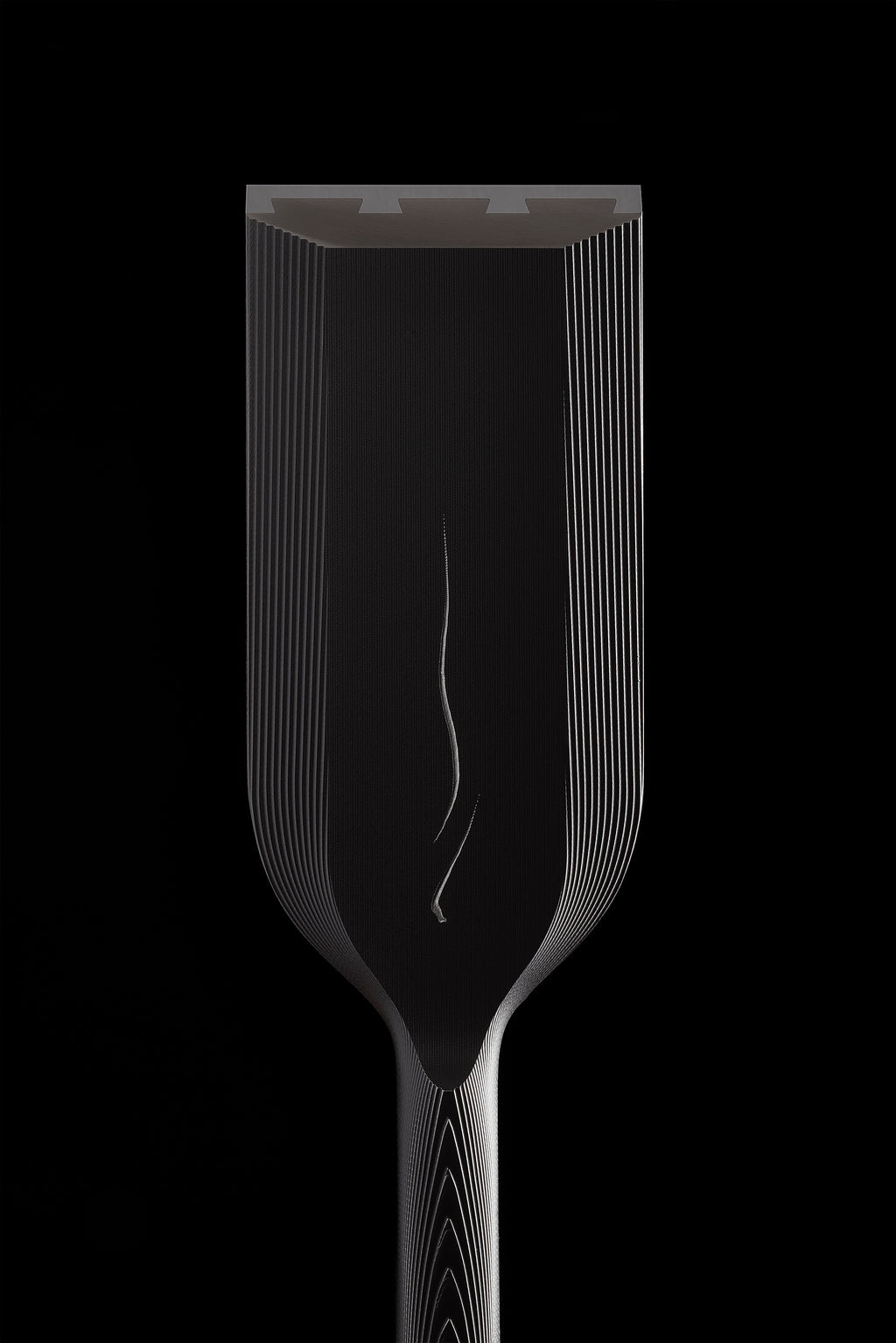 The wide DC-1 blade seen head on against black, mist line running down the center and the hollows visible along the cutting edge