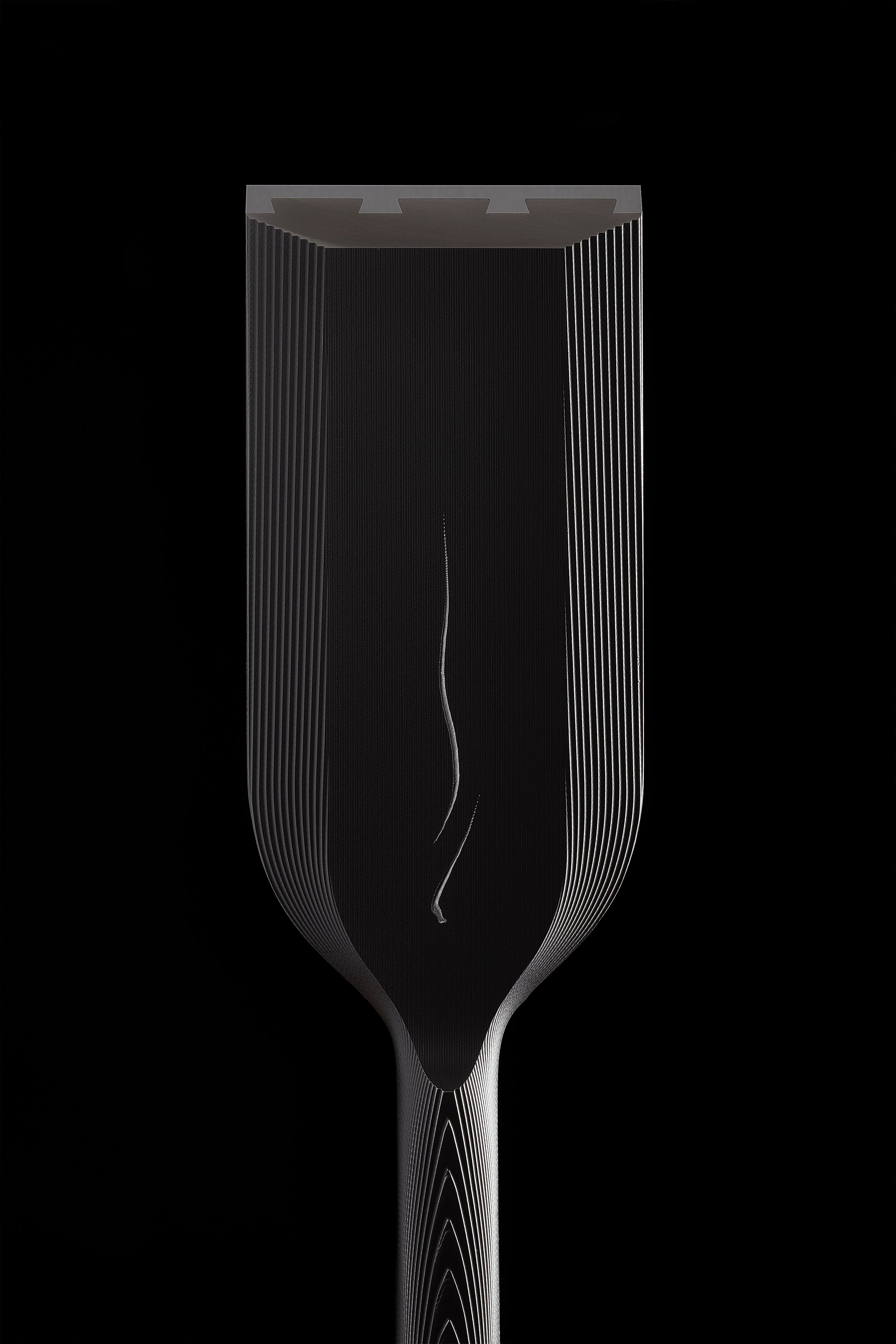 The wide DC-1 blade seen head on against black, mist line running down the center and the hollows visible along the cutting edge