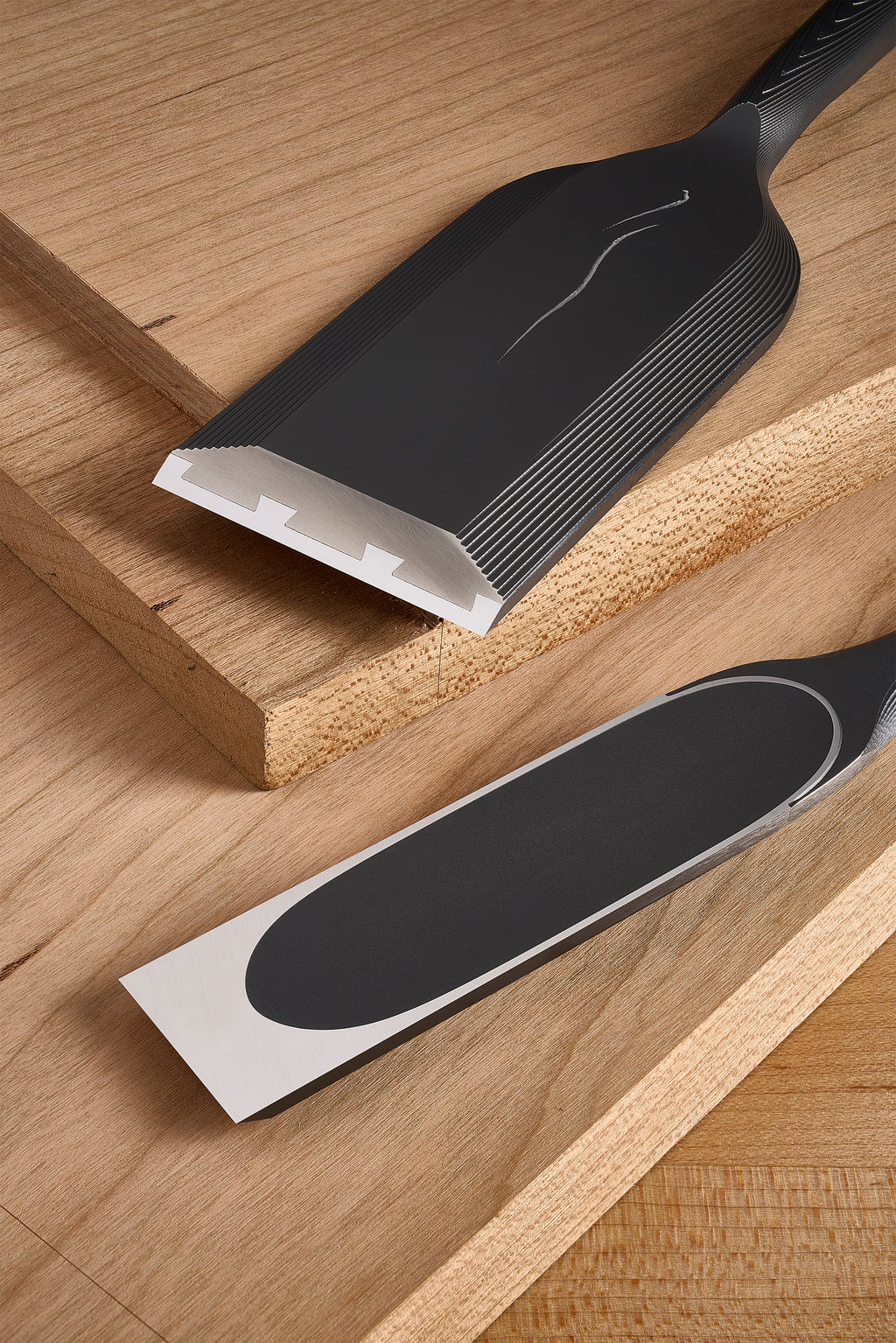 Both DC-1 chisels on a board, one showing the hollows at the cutting edge, the other the oval hollow on its back