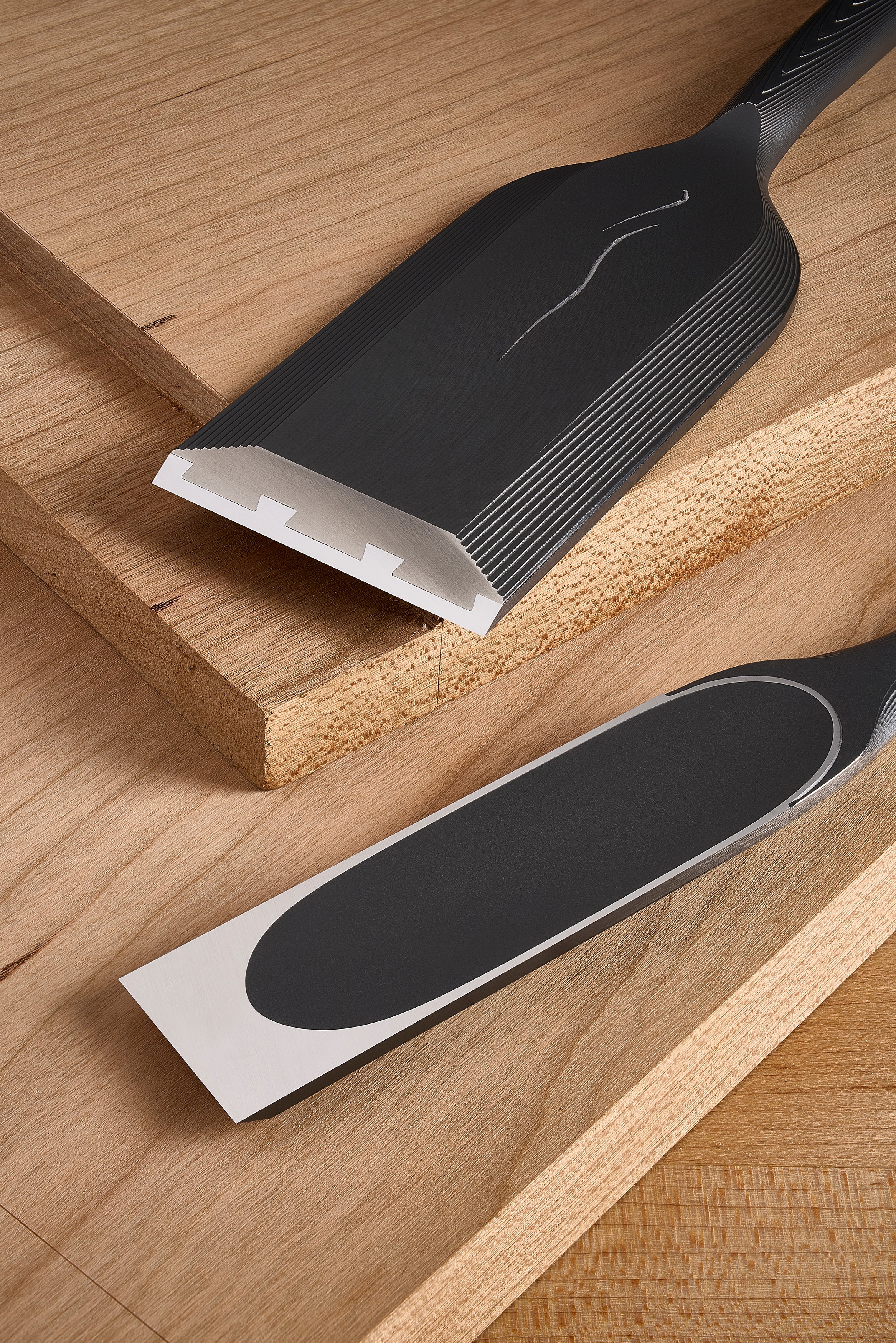 Both DC-1 chisels on a board, one showing the hollows at the cutting edge, the other the oval hollow on its back