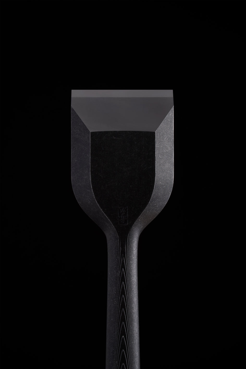 Bevel face of a wide TB-1 chisel, blackened body above the polished cutting edge