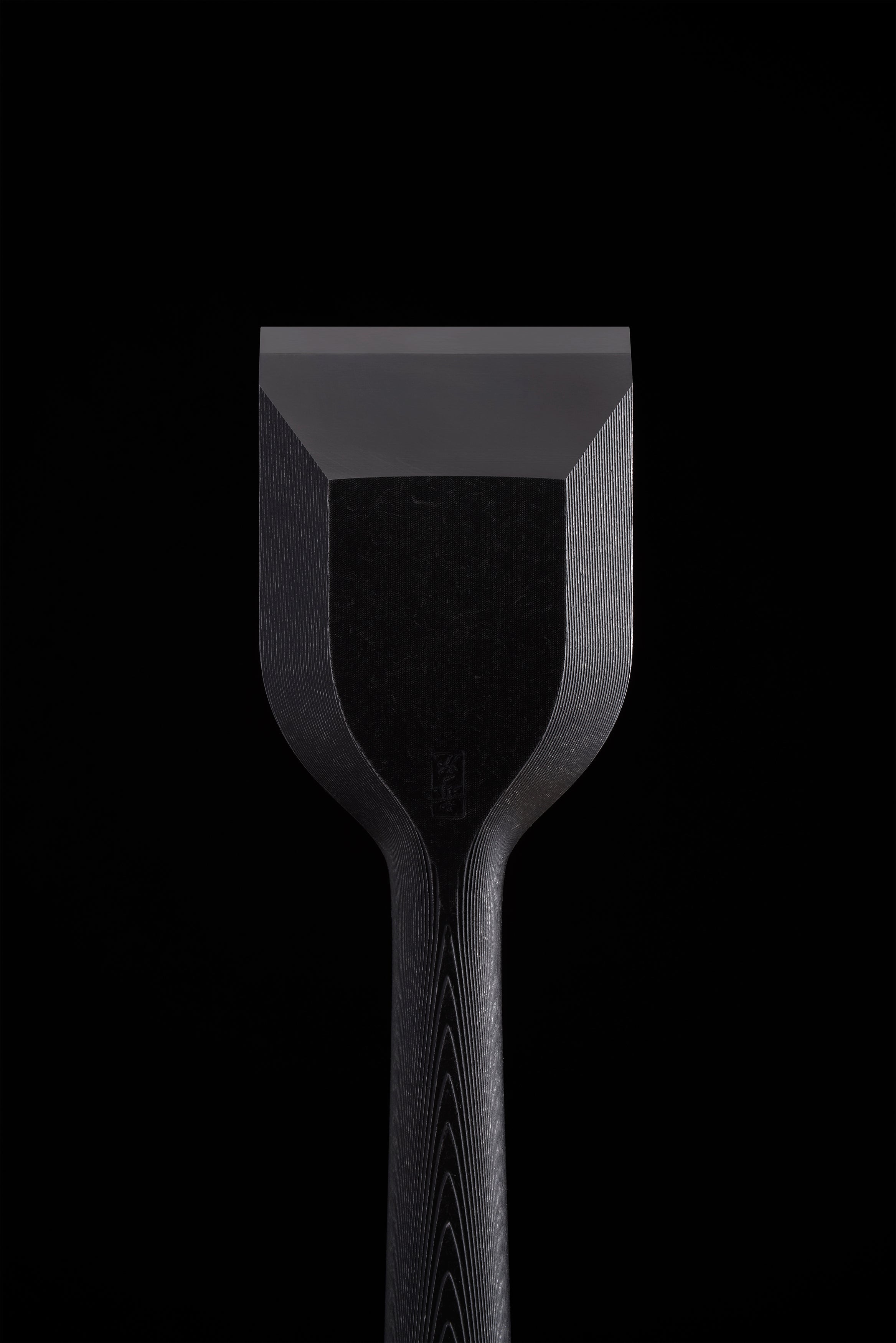 Bevel face of a wide TB-1 chisel, blackened body above the polished cutting edge