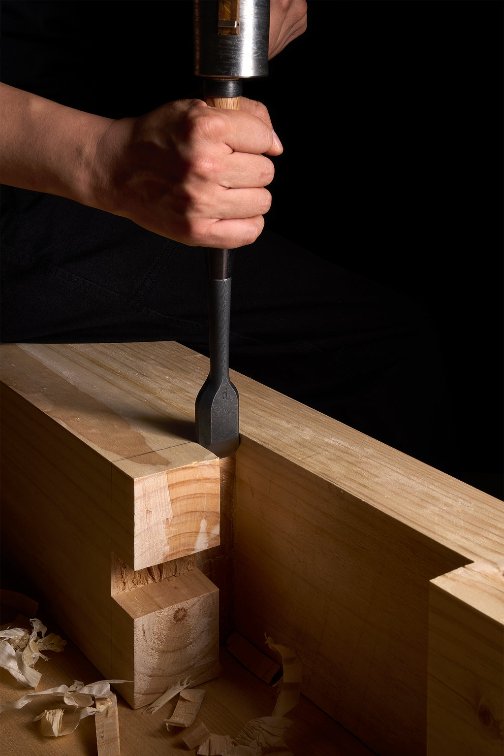 Driving a TB-1 chisel into a timber shoulder with a hammer, shavings on the bench
